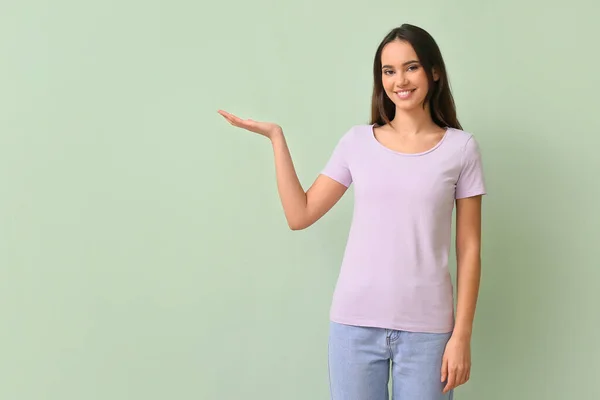 Ładna Młoda Kobieta Stylowej Koszulce Pokazuje Coś Zielonym Tle — Zdjęcie stockowe