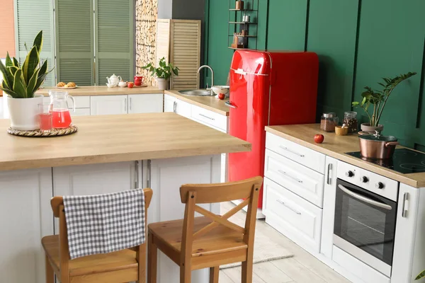 Modern mutfak, yemek masası, şık buzdolabı ve tezgahlar.