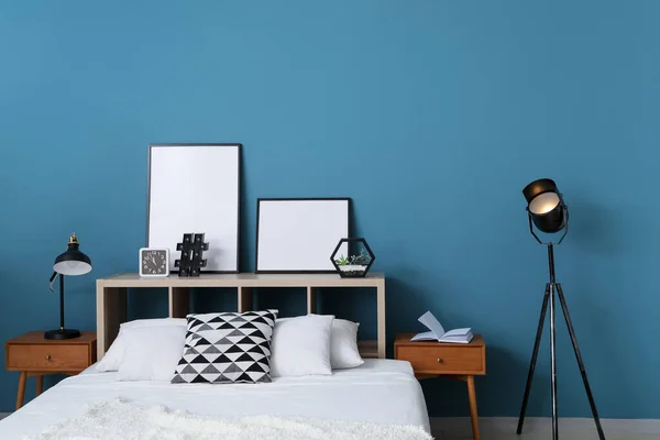 Kényelmes Ágy Lámpák Üres Plakátok Polcon Kék Fal Mellett — Stock Fotó