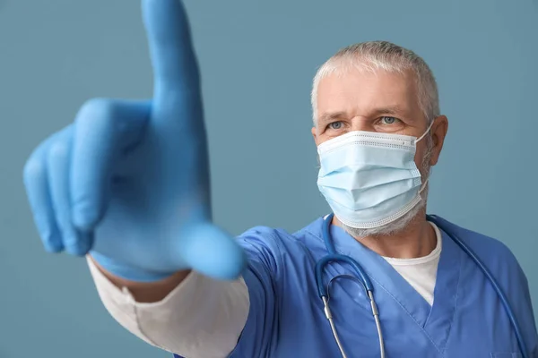 Mature Male Doctor Medical Mask Raised Index Finger Blue Background — Stock Photo, Image