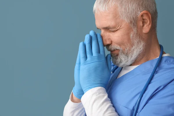 Mature Male Doctor Praying Blue Background — Stock Photo, Image