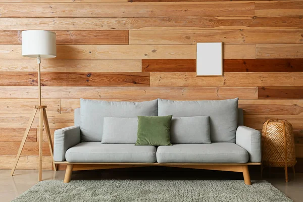 居室内部木制墙壁上舒适的沙发 落地灯和空白相框 — 图库照片