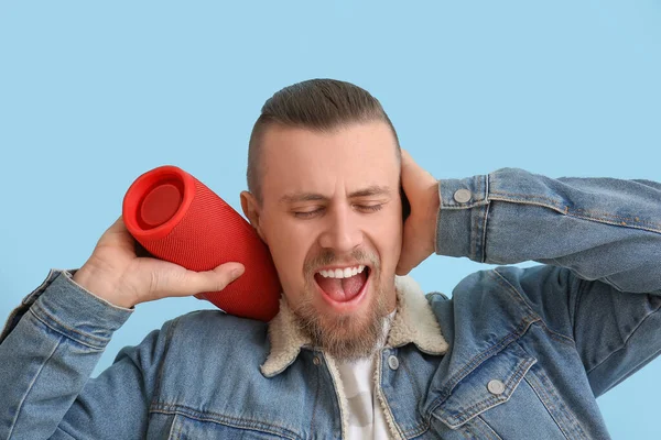 Emotional Man Holding Wireless Portable Speaker Closing Ears Blue Background — Stock Photo, Image