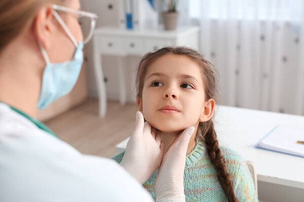 Doctor examining little girl's neck in clinic