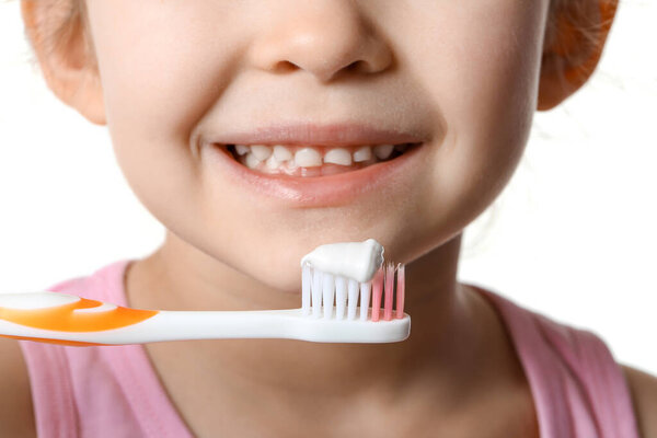 Adorable little girl and tooth brush with paste on white background, closeup