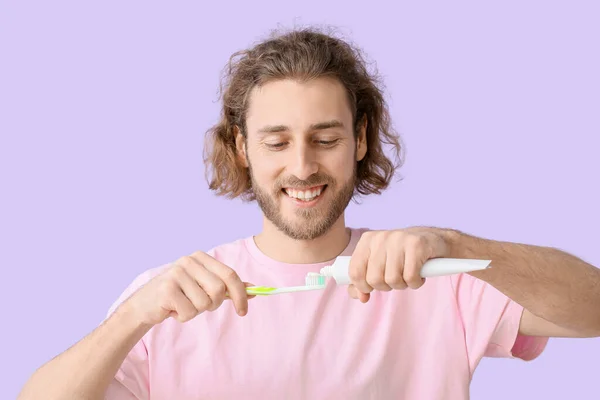 Young Man Applying Tooth Paste Brush Lilac Background — Stock Photo, Image