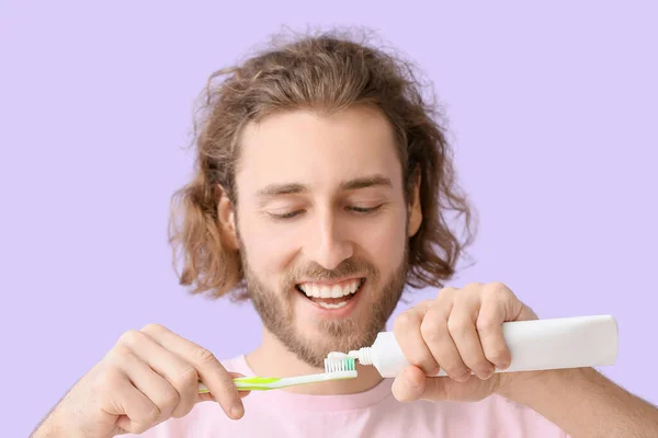 Young Man Applying Tooth Paste Brush Lilac Background Closeup — Stock Photo, Image