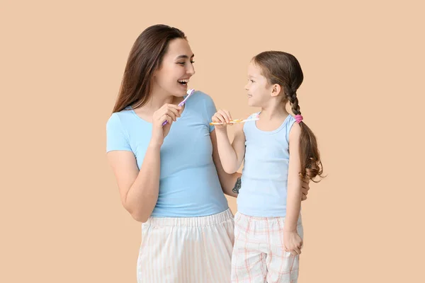 女の子とともに彼女の母ブラッシング歯上のベージュ背景 — ストック写真