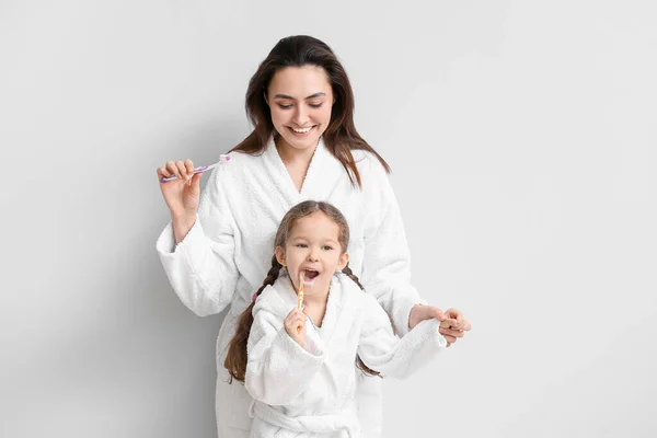 小さな女の子とともに彼女の母ブラッシング歯上の光の背景 — ストック写真