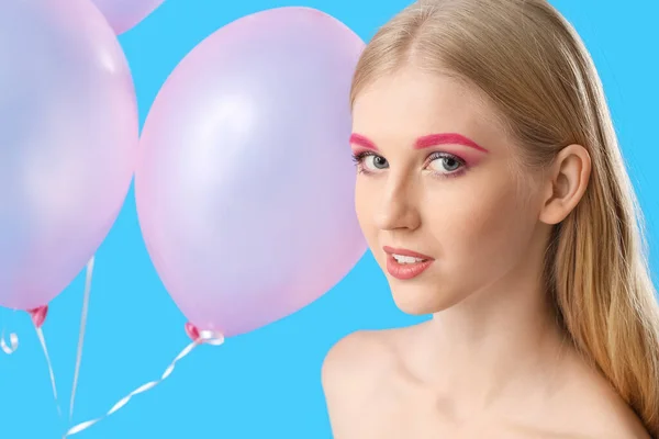 若いです女性とともに臨時化粧保持空気風船上の色背景 — ストック写真