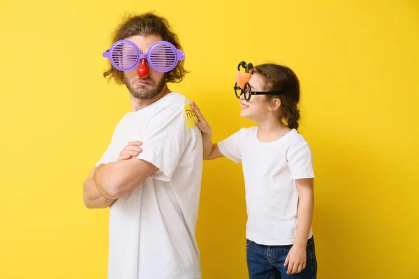 Niña Jugando Una Broma Padre Contra Fondo Amarillo Celebración Del — Foto de Stock