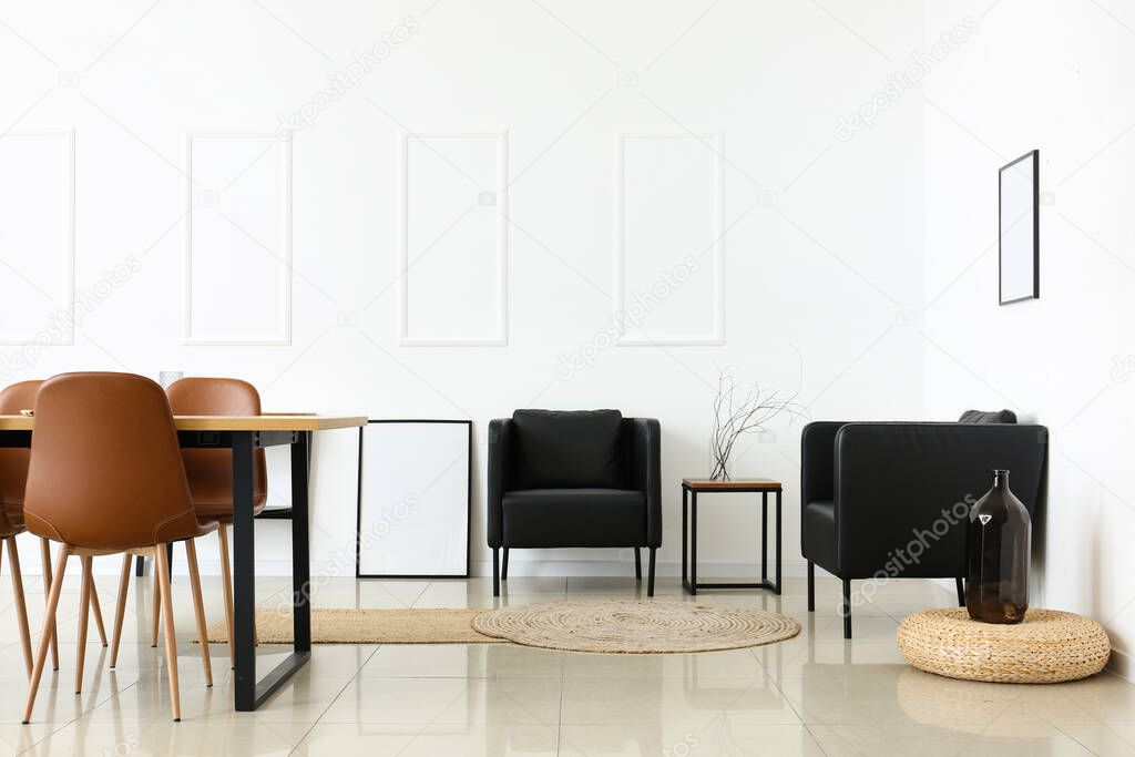 Interior of light dining room with table and black armchairs
