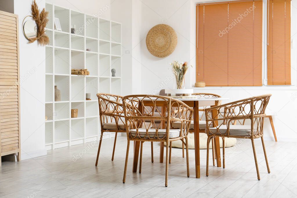 Interior of light dining room with table and shelving unit