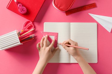 Pembe arka planda farklı kırtasiye malzemesi olan çocuk elleri