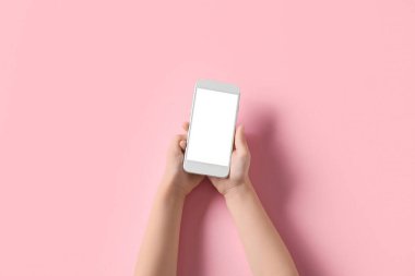 Pembe arka planda cep telefonu olan çocuk elleri
