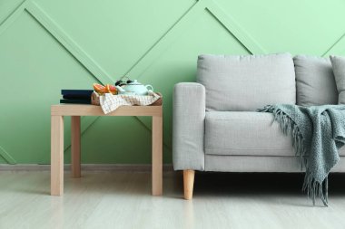 Şık bir kanepe ve yeşil duvarın yanındaki masa.