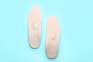 Mavi arka planda bir çift deri ortopedik taban.