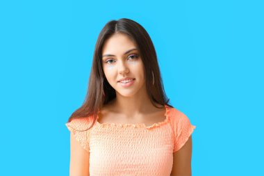 Mavi arka planda yaratıcı makyajlı genç bir kadının portresi.