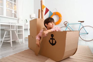 Sevimli küçük çocuk evde karton gemi ile oynamak