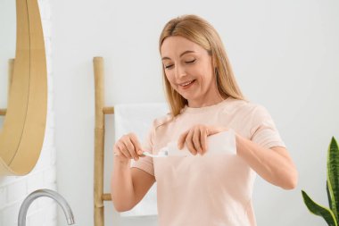 Güzel olgun bir kadın banyoda dişlerini fırçalıyor.