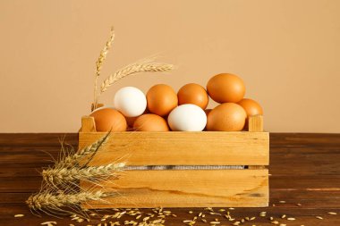 Duvarın yanındaki masada taze tavuk yumurtaları olan ahşap kutu.