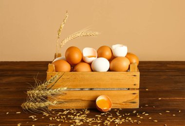 Duvarın yanındaki masada taze tavuk yumurtaları olan ahşap kutu.