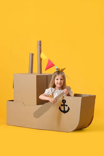 Cute Little Girl Playing Cardboard Ship Yellow Background — Stock Photo, Image