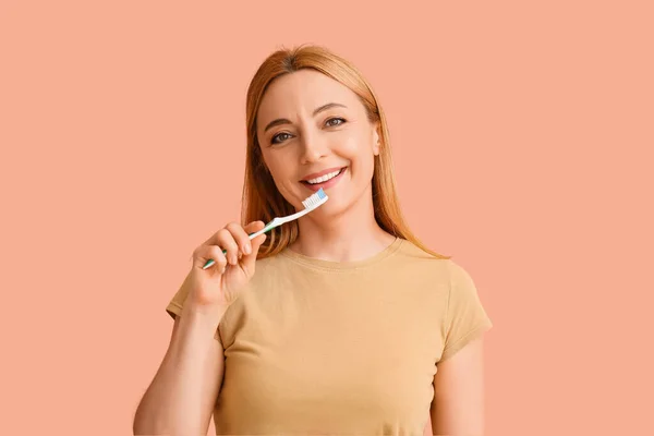 漂亮的成熟女人用彩色背景刷牙 — 图库照片