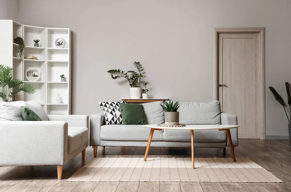 Oturma odasının içinde kahve masası, kanepeler ve bitkiler var.