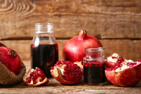 Kavanozlar dolusu nar pekmez ve ahşap zemin üzerinde taze meyveler.