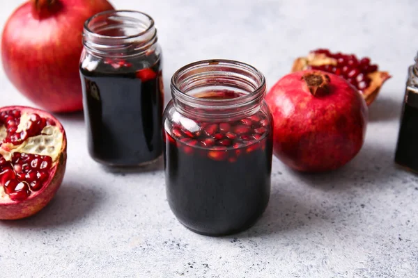 Kavanozlar dolusu nar pekmez ve arka planda taze meyveler.