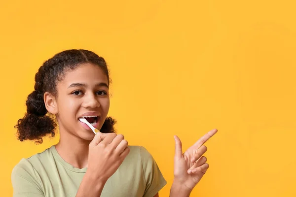 African American Teenage Girl Brushing Teeth Pointing Something Yellow Background — Stock Photo, Image