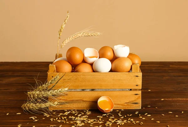 Duvarın yanındaki masada taze tavuk yumurtaları olan ahşap kutu.