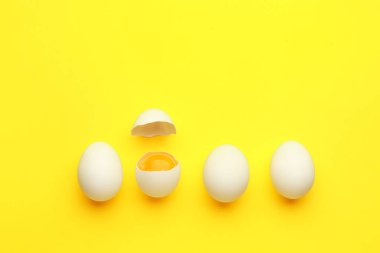 Kırılmış ve sarı arka planda bütün tavuk yumurtaları