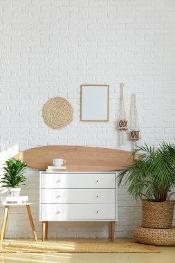 Ahşap sörf tahtası, klozet ve ev bitkileriyle aydınlatma odasının içinde.