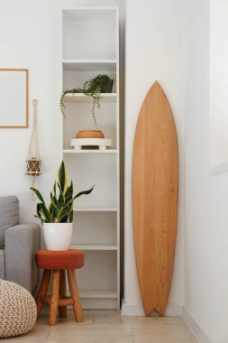 Ahşap sörf tahtası ve raf ünitesiyle aydınlık oturma odasının içinde.
