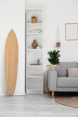 Ahşap sörf tahtası ve raf ünitesiyle aydınlık oturma odasının içinde.