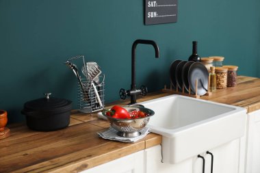 Seramik lavabo yemek ve mutfak gereçleriyle ahşap tezgahlarda renk duvarının yanında.