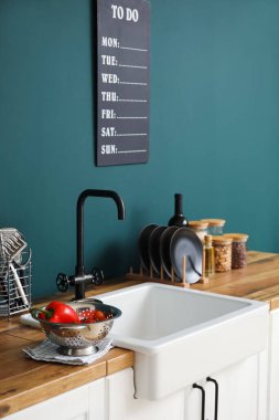 Seramik lavabo yemek ve mutfak gereçleriyle ahşap tezgahlarda renk duvarının yanında.