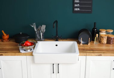 Seramik lavabo yemek ve mutfak gereçleriyle ahşap tezgahlarda renk duvarının yanında.