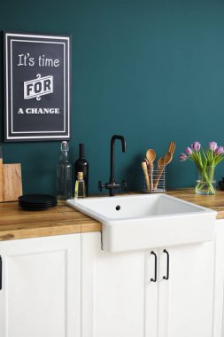 Lavabolu tezgahlar, vazodaki laleler ve renkli duvarların yanındaki mutfak aletleri.