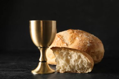 Koyu arkaplanda ekmek olan bir bardak şarap.