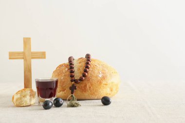 Ekmekli şarap, tespih ve arka planda haç.