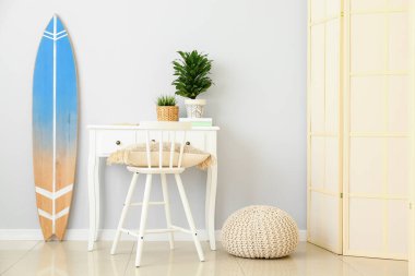 Işık duvarının yanında ev bitkileri ve sörf tahtaları olan bir işyeri