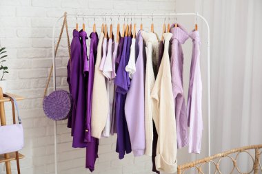 Beyaz tuğla duvarın yanında giysilerle dizilin.