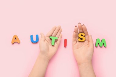 Pembe arka planda kelime AUTISM ile kadın ve çocuk