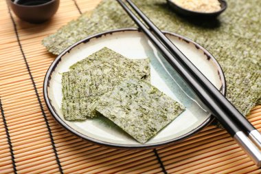 Lezzetli deniz yosunu çarşafları ve bambu hasırlı çubuklarla dolu bir tabak.