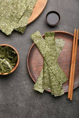 Lezzetli bir tabak yosun ve siyah arka planda soya soslu bir kase.