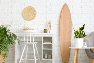 Tahta sörf tahtası, işyeri ve ev bitkileriyle aydınlık oturma odasının içi