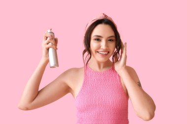 Pembe arka planda saç spreyi olan güzel bir kadın.